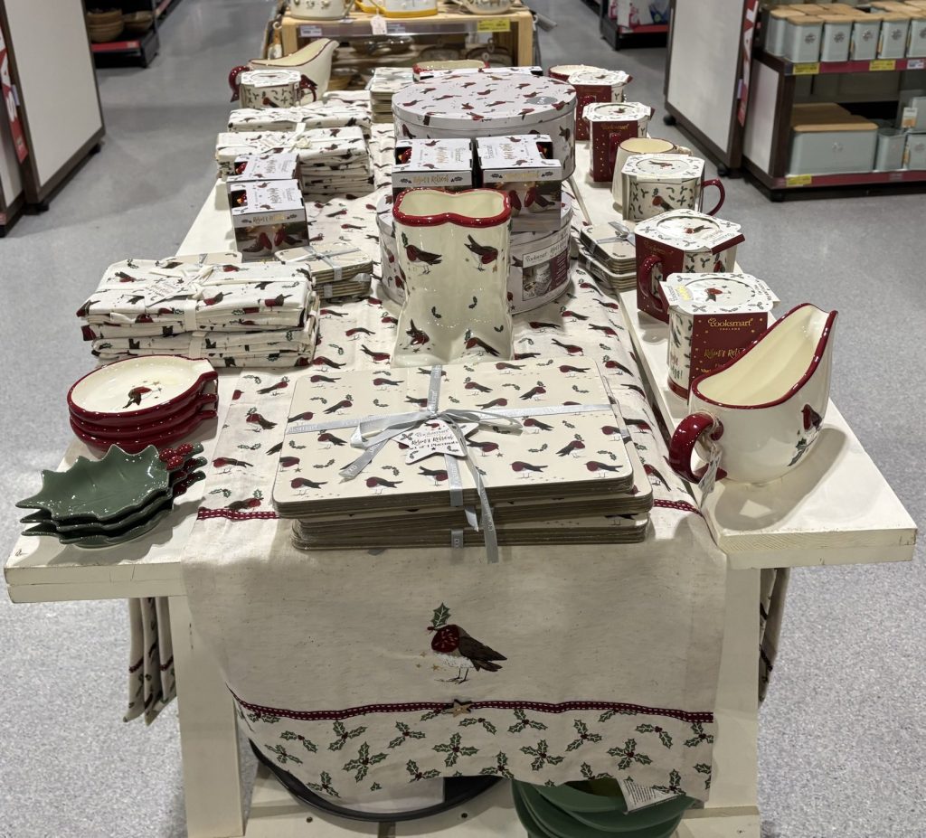 A table of Cooksmart Robin’s Retreat placemats, tins, mugs and gravy boats in a customer’s shop
